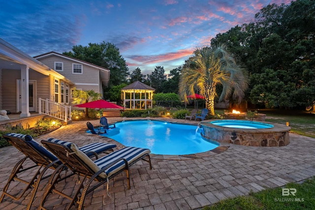20011 Lawrence Rd, Fairhope, AL 36532 - pool at dusk featuring a patio, a pool with connected hot tub, a gazebo, and an outdoor fire pit