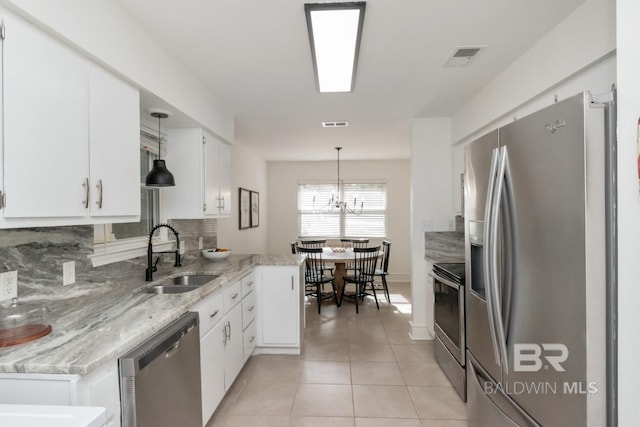 kitchen featuring sink, appliances with stainless steel finishes, decorative backsplash, white cabinets, and decorative light fixtures