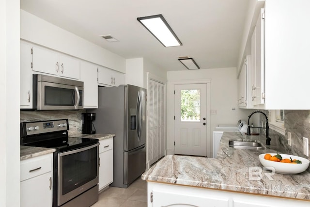 kitchen featuring appliances with stainless steel finishes, tasteful backsplash, sink, white cabinets, and kitchen peninsula