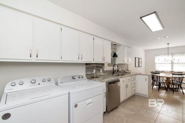 clothes washing area featuring light tile patterned flooring, sink, washing machine and clothes dryer, and a chandelier