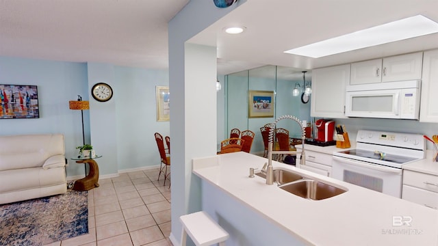 kitchen featuring light tile patterned floors, white cabinets, white appliances, and sink