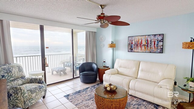 living room with light tile patterned floors, a textured ceiling, a water view, and ceiling fan