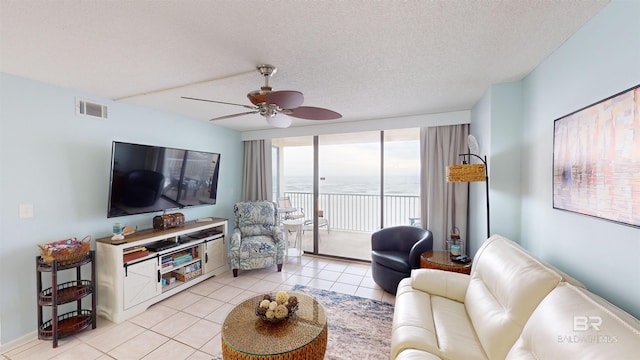 tiled living room with a textured ceiling, a wall of windows, and ceiling fan