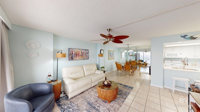 living room featuring ceiling fan, sink, light tile patterned floors, and a textured ceiling