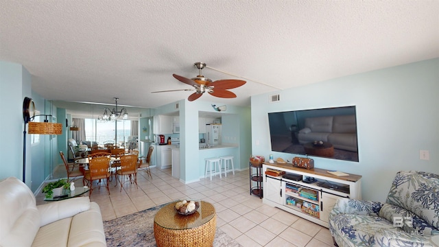 tiled living room featuring a textured ceiling and ceiling fan with notable chandelier