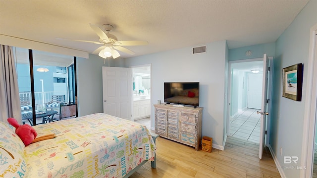 bedroom featuring ceiling fan, light hardwood / wood-style floors, a textured ceiling, and connected bathroom