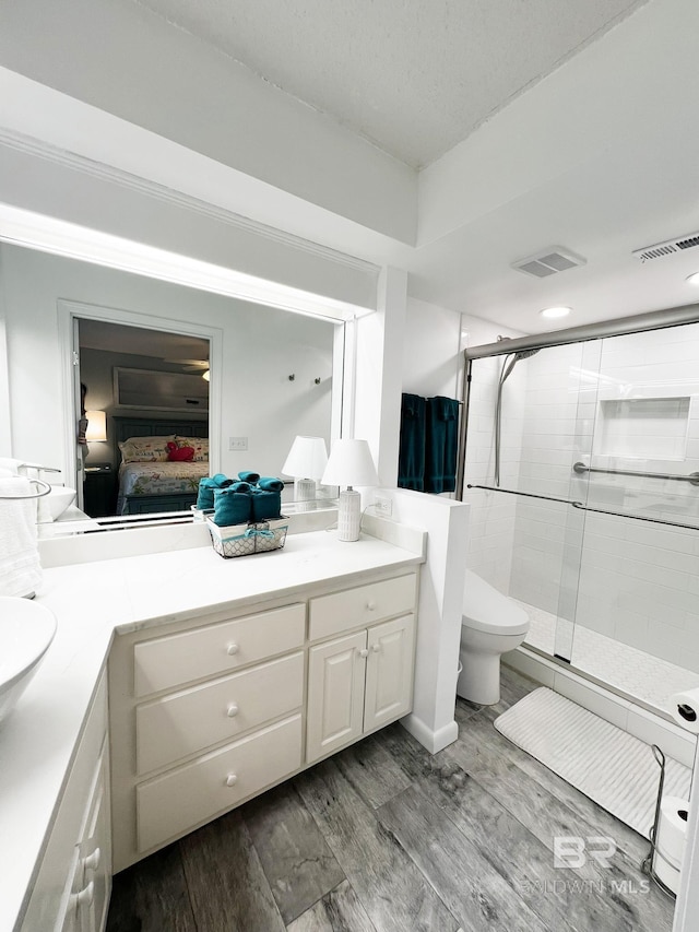 bathroom with hardwood / wood-style floors, vanity, toilet, and walk in shower