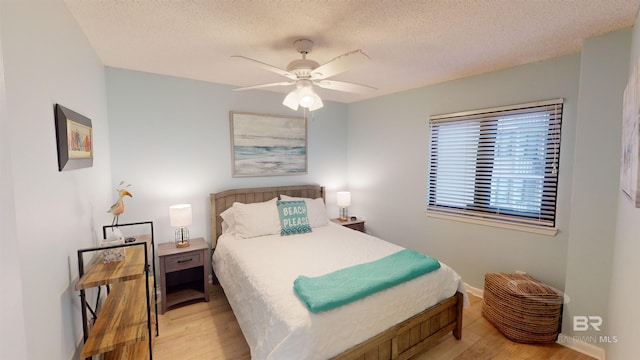 bedroom with ceiling fan, light hardwood / wood-style floors, and a textured ceiling