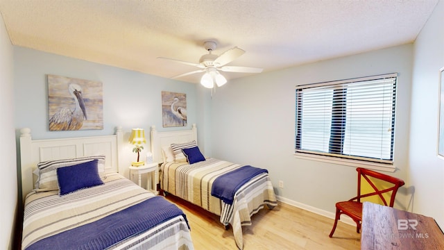 bedroom with ceiling fan, light hardwood / wood-style floors, and a textured ceiling