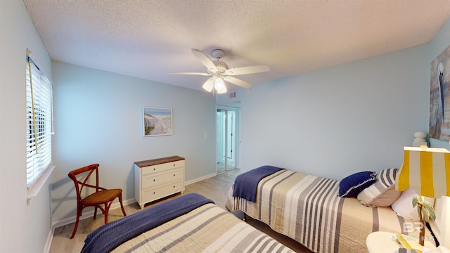 bedroom with ceiling fan, light wood-type flooring, and a textured ceiling