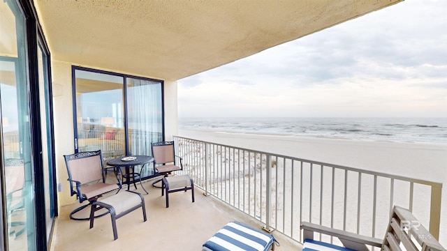 balcony featuring a water view and a beach view