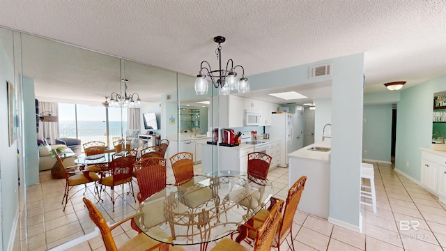 tiled dining area with sink, a textured ceiling, and an inviting chandelier