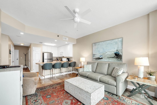 living room with a ceiling fan and baseboards