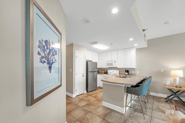 kitchen featuring white appliances, a peninsula, a sink, baseboards, and light countertops