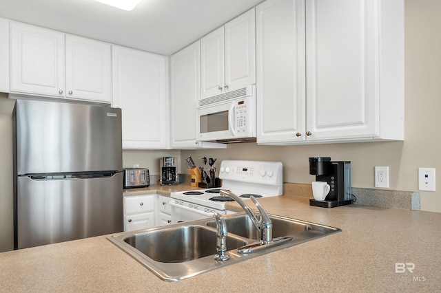 kitchen with white appliances, a sink, white cabinetry, and light countertops