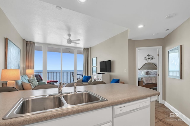 kitchen with white dishwasher, open floor plan, a sink, ceiling fan, and light tile patterned floors