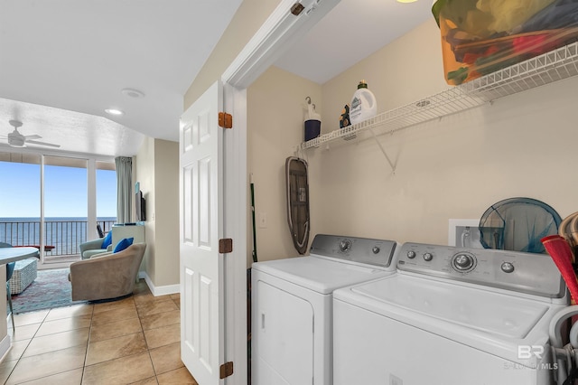 clothes washing area with washer and clothes dryer, a ceiling fan, light tile patterned floors, and baseboards