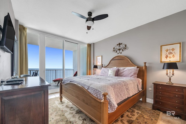 bedroom with access to outside, a water view, light tile patterned flooring, and ceiling fan