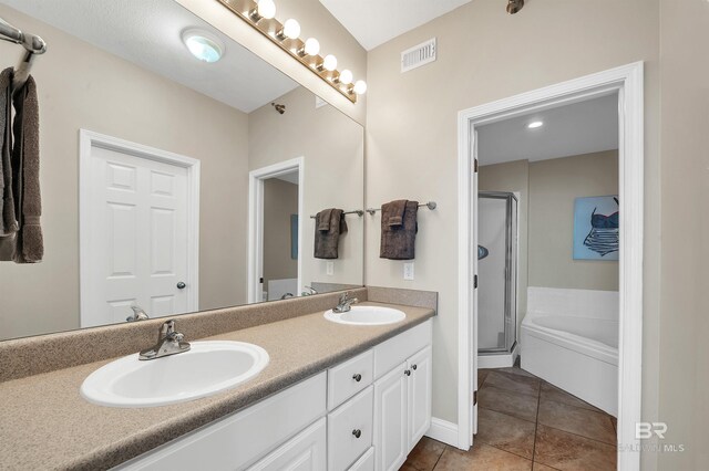 bathroom featuring a stall shower, tile patterned floors, double vanity, a garden tub, and baseboards