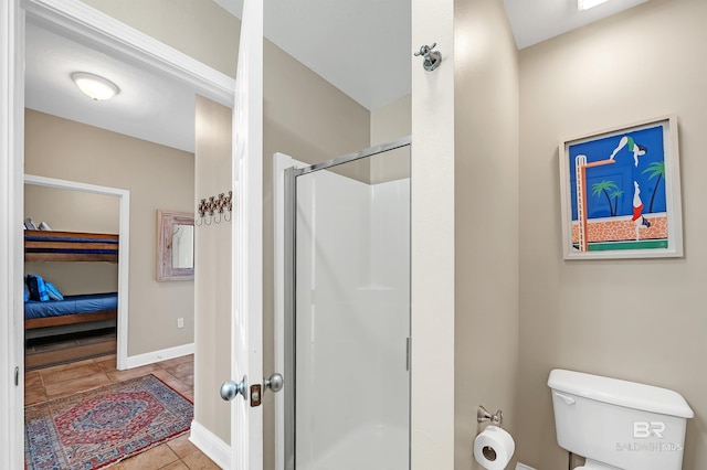 ensuite bathroom featuring a shower stall, toilet, tile patterned floors, and baseboards