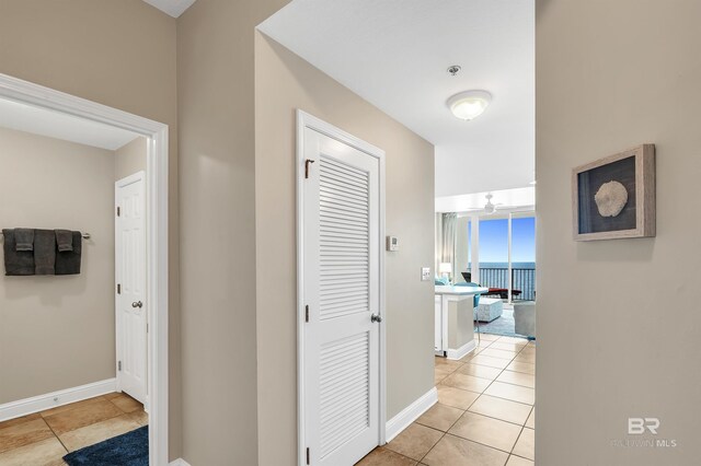 hallway with light tile patterned floors and baseboards