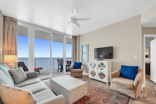 tiled living room with ceiling fan and baseboards