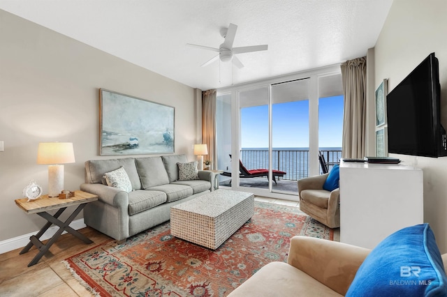 living room with ceiling fan and baseboards