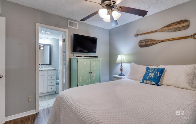 bedroom featuring visible vents, ensuite bath, ceiling fan, wood finished floors, and a textured ceiling