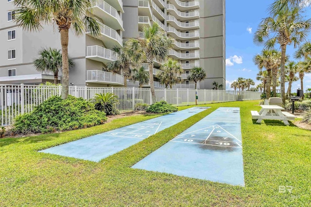 view of property's community with a yard, shuffleboard, and fence