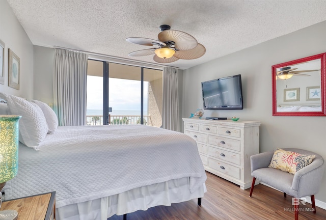 bedroom with access to exterior, ceiling fan, a textured ceiling, and wood finished floors