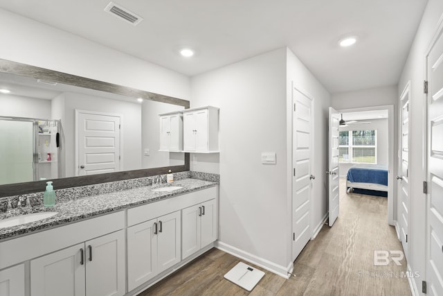 ensuite bathroom featuring visible vents, a sink, and wood finished floors