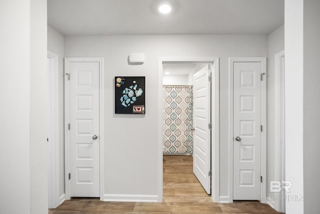 hall with baseboards and wood finished floors