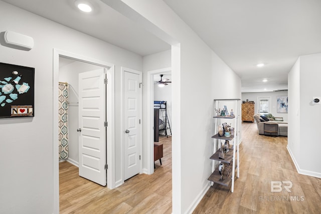 hallway with light wood-type flooring, baseboards, and recessed lighting