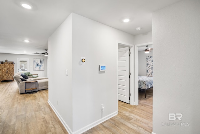 hall featuring light wood finished floors, baseboards, and recessed lighting