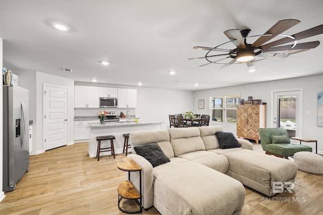 living room featuring light wood-style floors, ceiling fan, visible vents, and recessed lighting