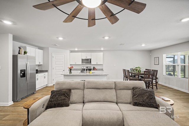 living room featuring baseboards, ceiling fan, light wood-type flooring, and recessed lighting