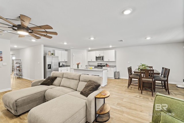 living area featuring recessed lighting, baseboards, and light wood finished floors