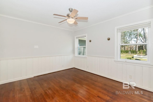 empty room featuring ceiling fan, wood finished floors, wainscoting, and ornamental molding