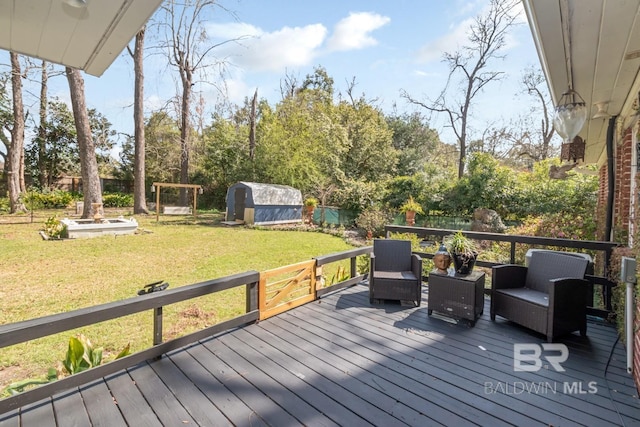 wooden deck with an outbuilding, a lawn, a storage unit, and fence