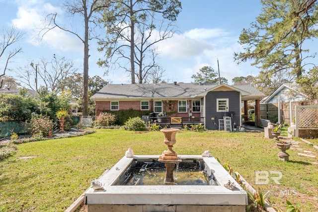 back of property featuring a yard, fence, and brick siding