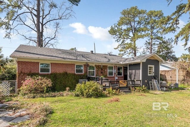 back of property featuring a wooden deck, brick siding, a yard, and fence