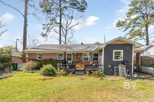 back of property with a yard, brick siding, a deck, and fence