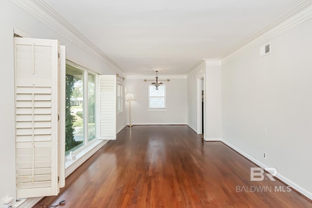 spare room featuring visible vents, dark wood-type flooring, ornamental molding, baseboards, and a chandelier