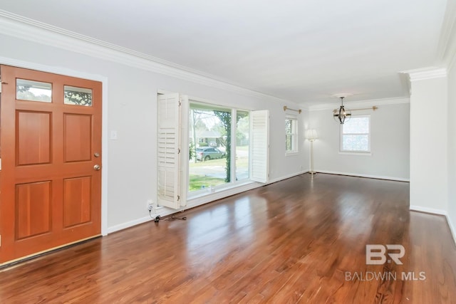 foyer entrance with a notable chandelier, crown molding, baseboards, and wood finished floors