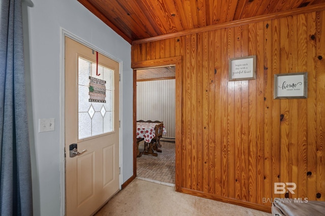 entryway with baseboard heating, light colored carpet, wood ceiling, and wood walls