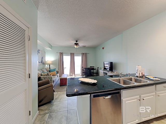 kitchen featuring stainless steel dishwasher, open floor plan, dark countertops, and a sink