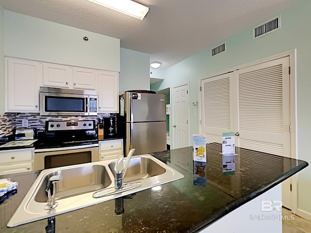 kitchen with decorative backsplash, white cabinets, visible vents, and appliances with stainless steel finishes