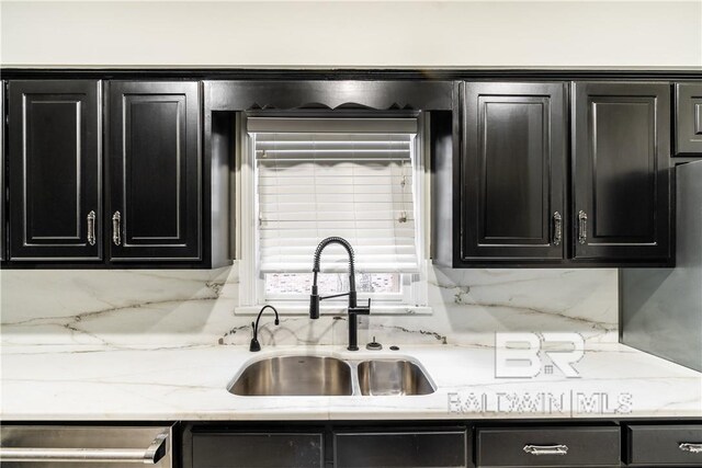 kitchen with stainless steel dishwasher, backsplash, light stone counters, and sink