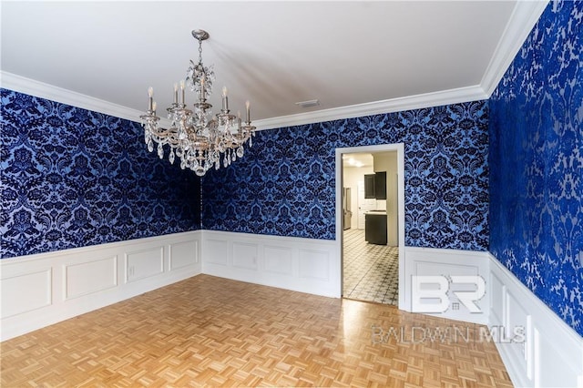 spare room with a chandelier, light parquet flooring, and ornamental molding