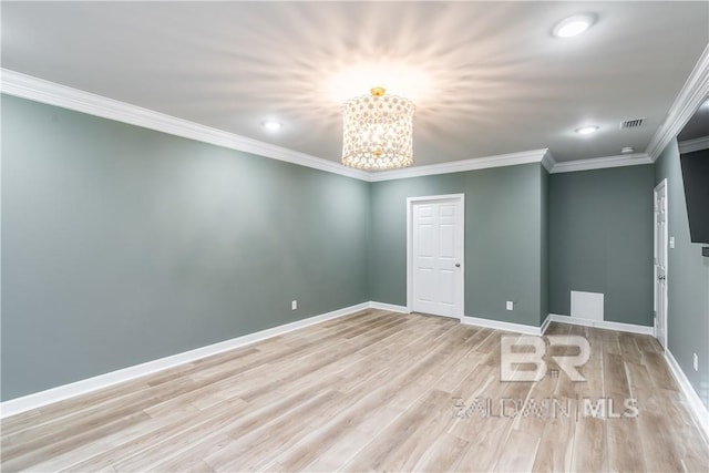 unfurnished room featuring crown molding, light hardwood / wood-style floors, and an inviting chandelier